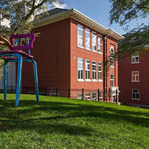 a playground with a blue and pink slide in front of a red building.