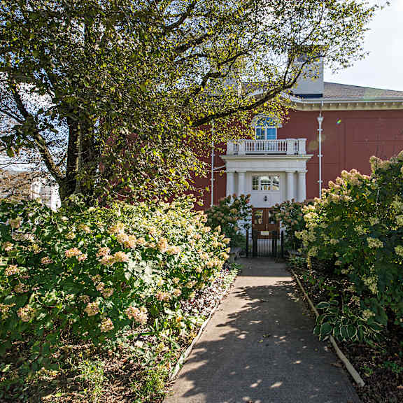 a pathway leads to a building with a balcony.