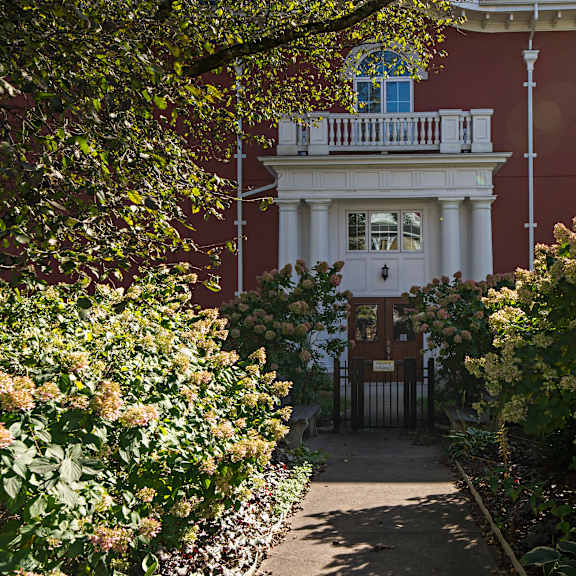 a white house with a balcony is surrounded by greenery.