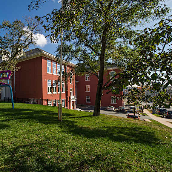 a playground with a swing set in front of a red building.
