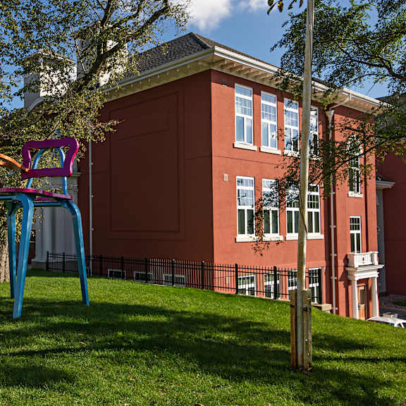 a playground with a blue and purple slide in front of a red building.