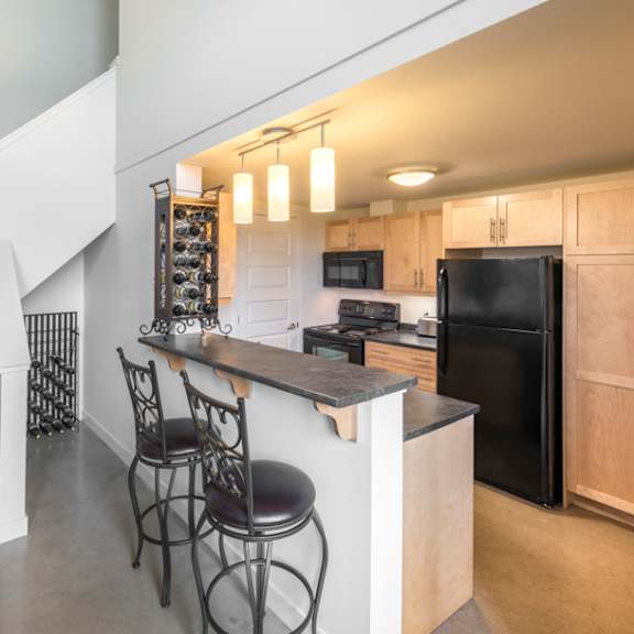 a kitchen with a black fridge and a black stool.