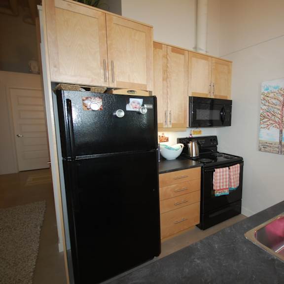 a black fridge in a kitchen with a pink towel in the sink.