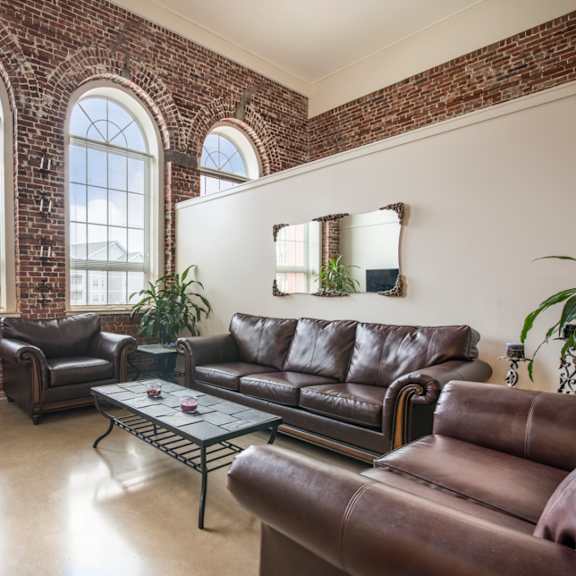 a living room with brown leather couches and a brick wall.