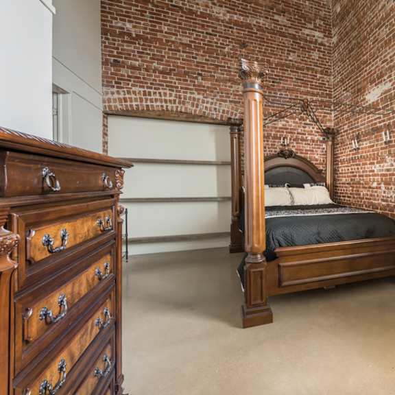 a bedroom with a brick wall and a bed.