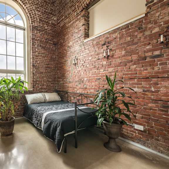 a bedroom with a bed, a potted plant, and a window.