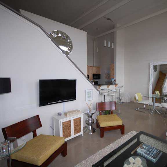 a living room with a white couch, a wooden chair, and a glass coffee table.