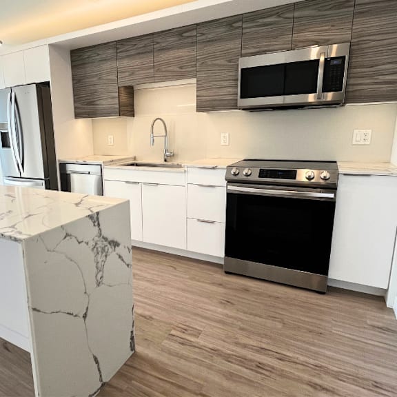 a modern kitchen with a marble island and stainless steel appliances.
