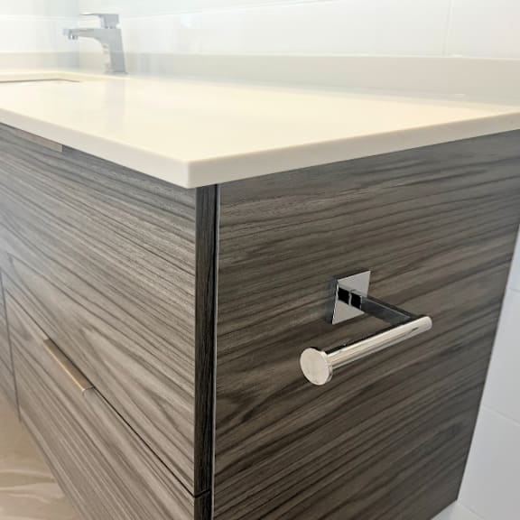 a modern bathroom vanity with a white countertop and dark wood drawers.