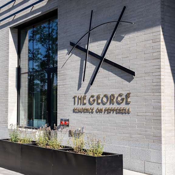 the george residence on pepperell is a modern building with a large window and a planter box in front.