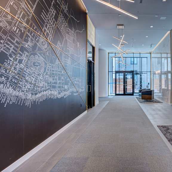 a hallway with a black and white floor plan on the wall and a black leather chair.
