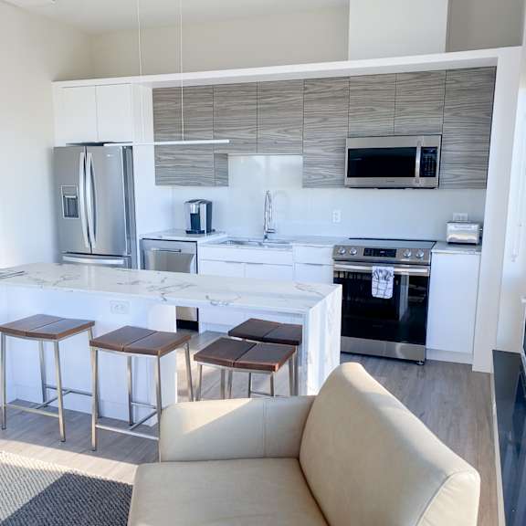 a modern kitchen with a refrigerator, microwave, oven, and sink.