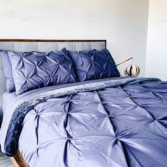 a bed with a blue comforter and matching pillows.