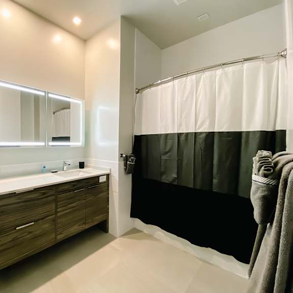 a bathroom with a toilet, sink, mirror, and shower.
