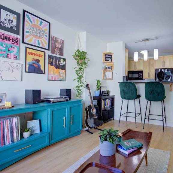 a living room with a green couch, a guitar, and a bookshelf.