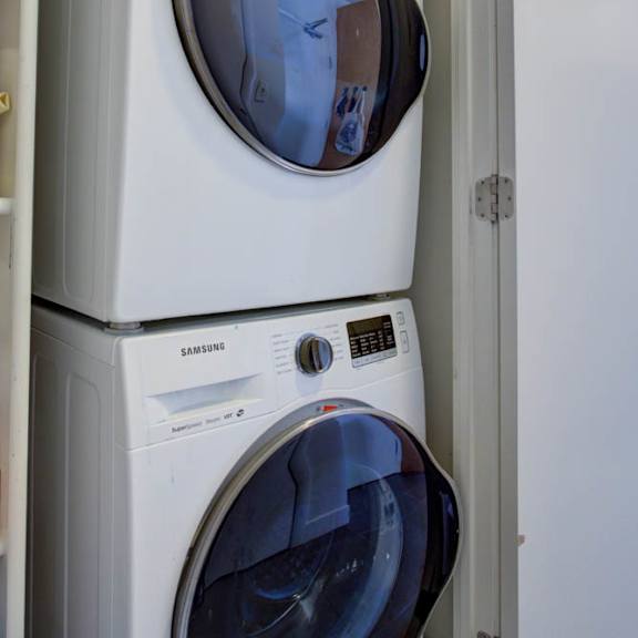 a stack of white washing machines with the top one being a samsung.