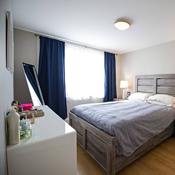 a bedroom with a bed, nightstand, and window with blue curtains.