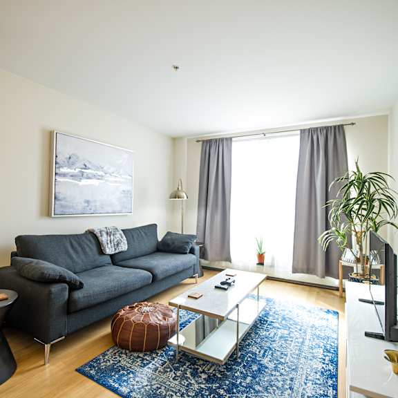 a living room with a grey couch, a coffee table, and a painting on the wall.