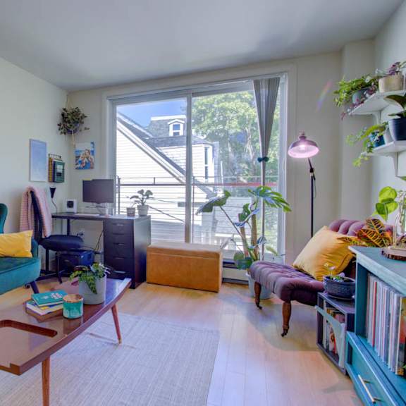a living room with a green couch and a round mirror on the wall.