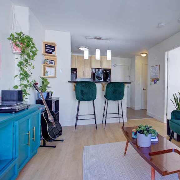 a living room with a green couch, a guitar, and a potted plant.