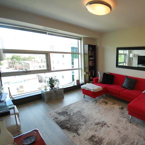 a red couch with a white ottoman in front of a large window.