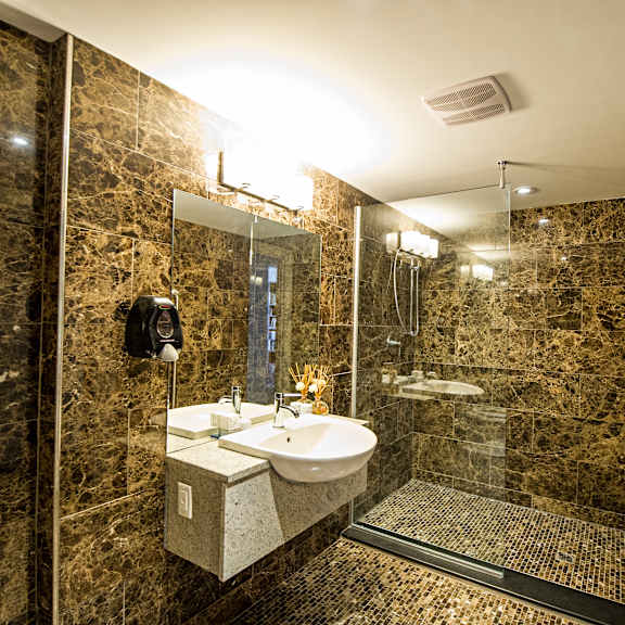 a bathroom with a marble wall and a glass shower stall.