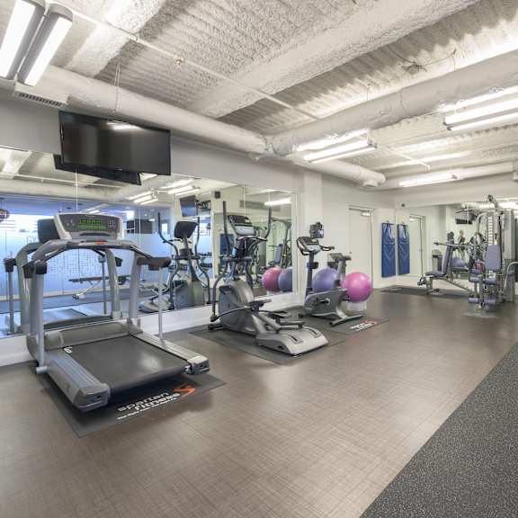 a spacious gym with a variety of equipment including treadmills, weights, and exercise machines.