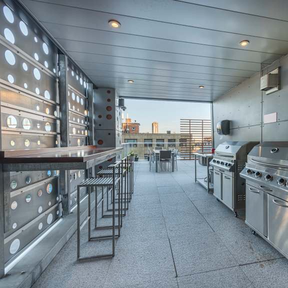 a long row of stainless steel ovens are lined up on a patio.