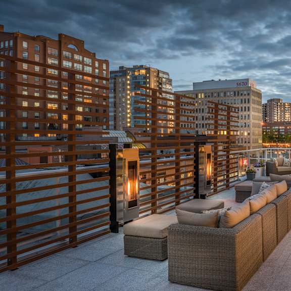 a rooftop patio with a railing and a couch.