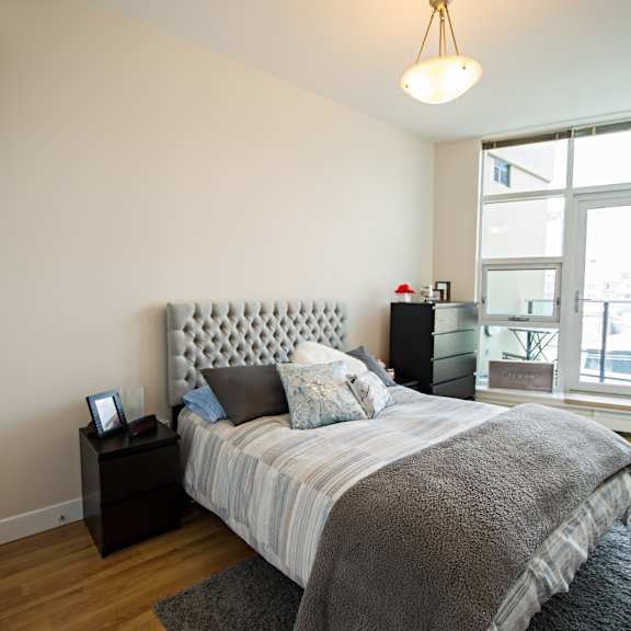 a bedroom with a large bed and a window overlooking a cityscape.