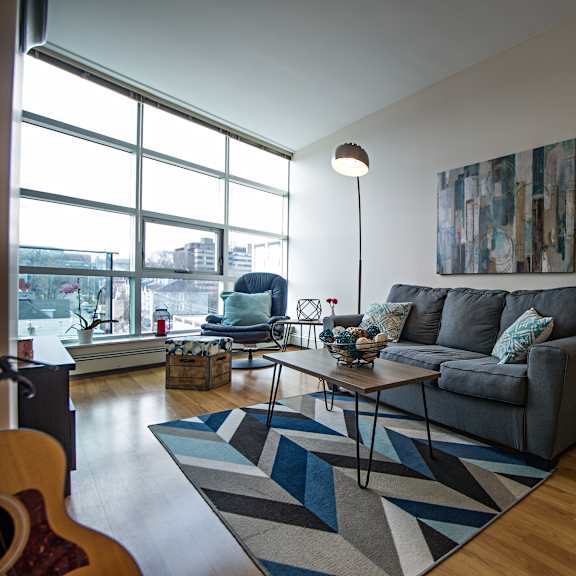 a living room with a grey couch and a guitar on the floor.