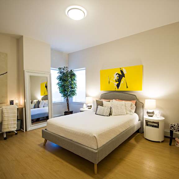 a bedroom with a bed, a chair, and a painting on the wall.