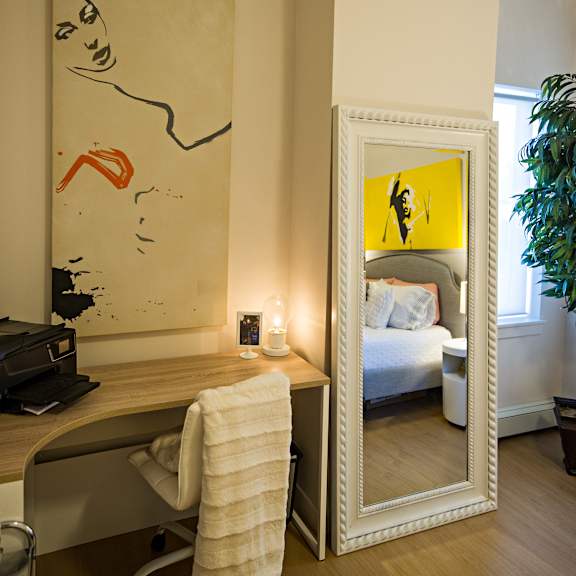 a large mirror reflects a bedroom with a bed and a plant.