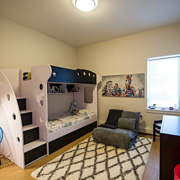 a room with a bunk bed, a chair, a couch, a rug, and a television.