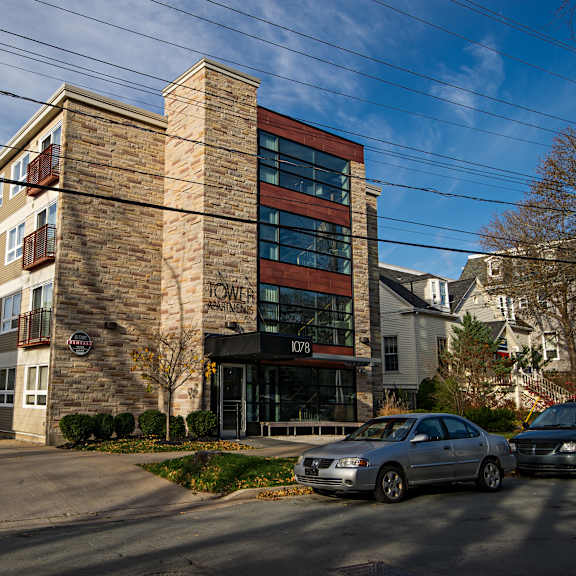 a modern building with a brick facade and a glass entrance is surrounded by parked cars.
