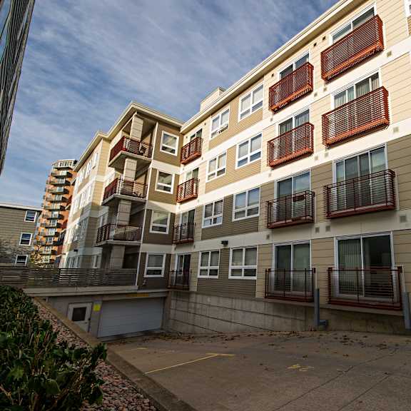 apartment building with brown and beige siding and red balcony railings.