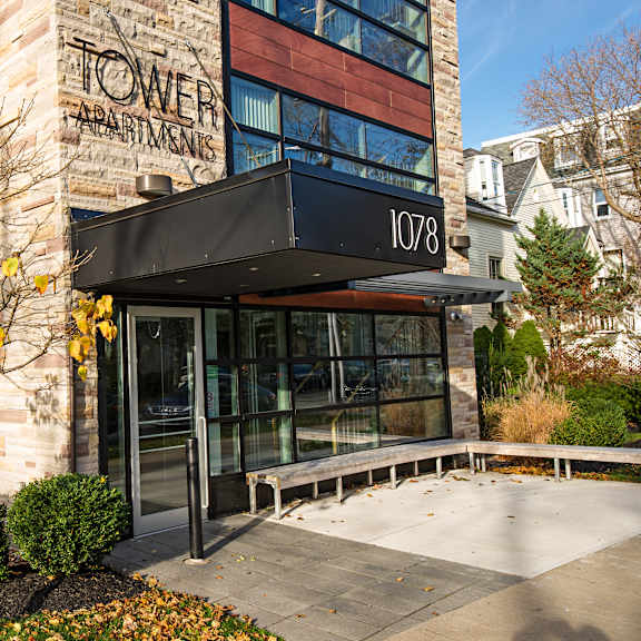 a tree with yellow leaves is in front of a building with a sign that says "tower apartments".