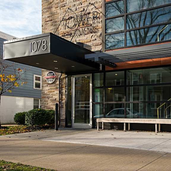 the entrance to a building with a glass door and a bench outside.