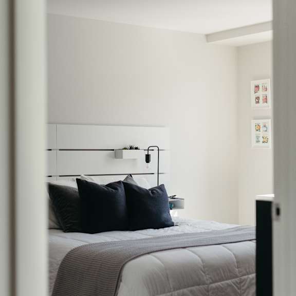 a bedroom with a bed and a wall-mounted shelf with pictures.