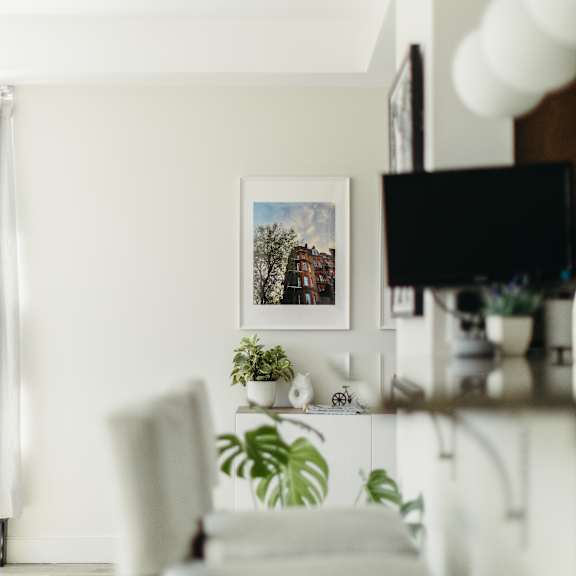 a white chair is in front of a shelf with a picture and plants on it.