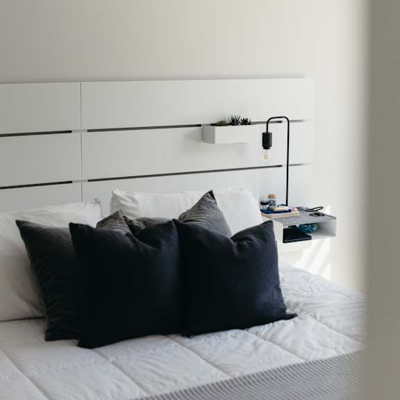 a bed with white sheets and black pillows.
