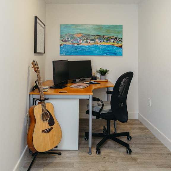 a room with a desk, chair, and a guitar.