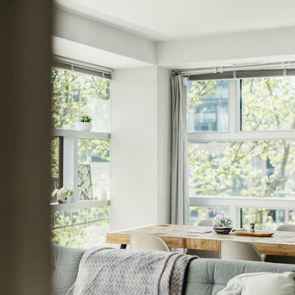 a table with a couch and a window with a view of trees.