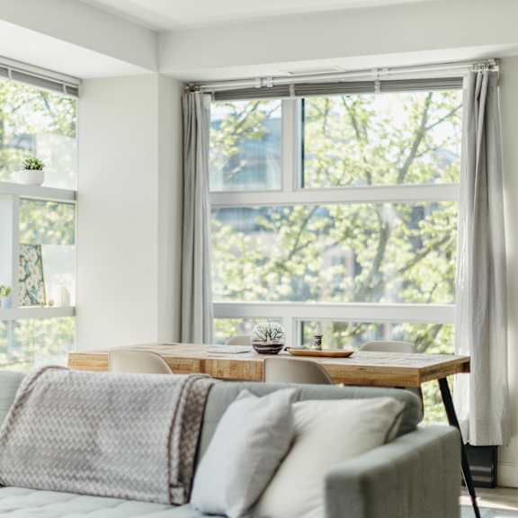 a living room with a couch, a table, and a window with a view of trees.