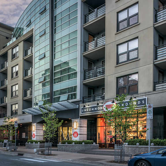 a modern apartment building with a glass facade is situated on a street corner.