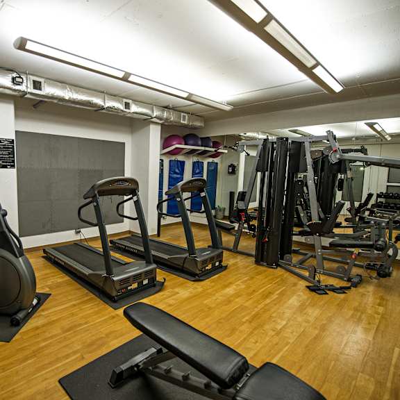 a gym with a variety of equipment including treadmills, weights, and exercise machines.