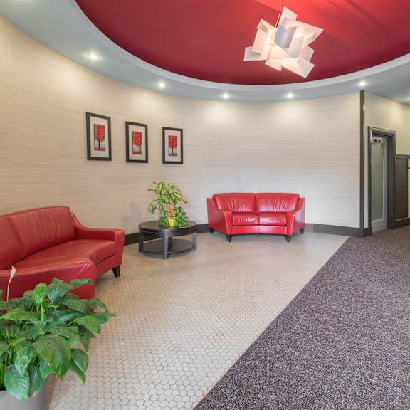 a red couch and a table with a vase on it are in a room with a red ceiling.