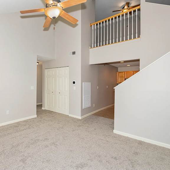 a room with a ceiling fan and a staircase.