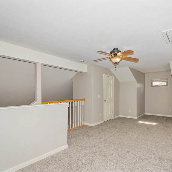 a room with a ceiling fan and carpeted floor.