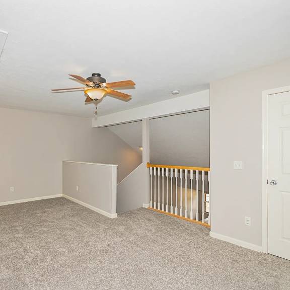 a room with a ceiling fan and carpeted floor.